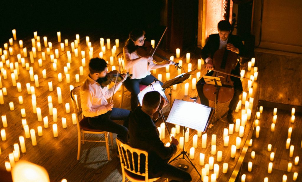 string quartet on stage performing surrounded by candles