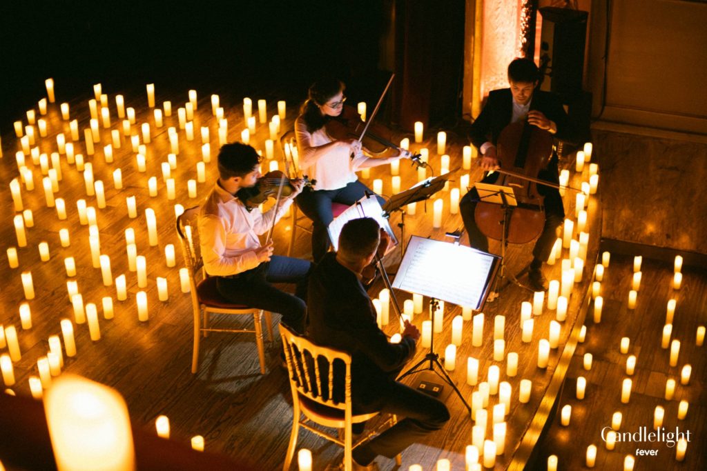 string quartet performing on stage surrounded by hundreds of candles