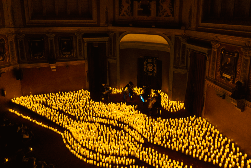 A string quartet playing on stage surrounded by candles