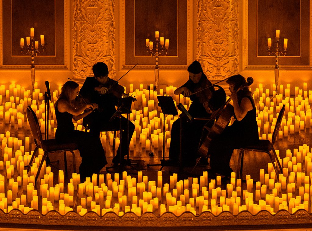 string quartet performing on stage surrounded by candles