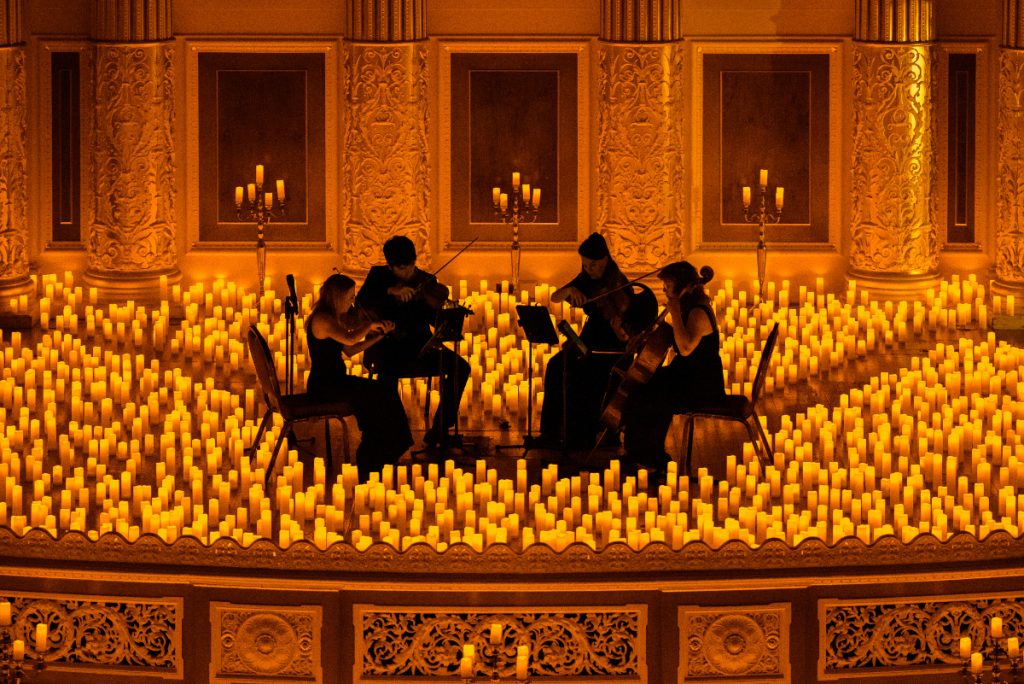 string quartet performing on stage surrounded by hundreds of candles