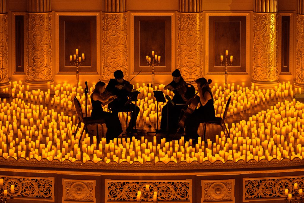 string quartet on stage performing surrounded by hundreds of candles