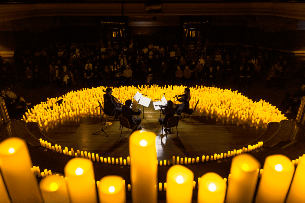 String quartet performing on stage surrounded by candles