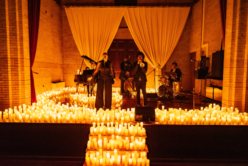 An array of musical performers on a stage covered by candles.