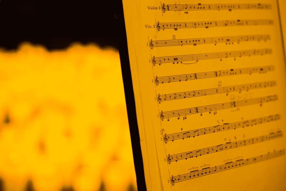 A close up of music sheets in the glow of candlelight.