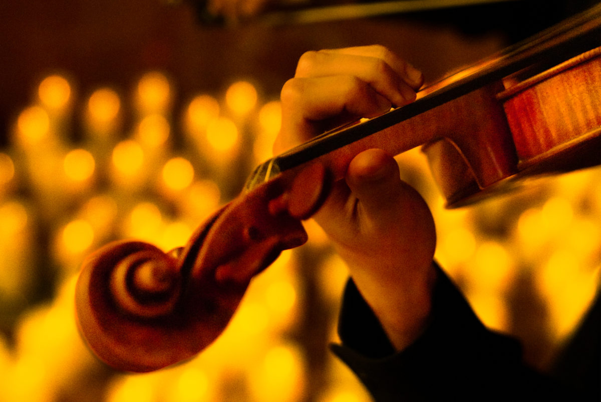 A close-up of a hand playing a string instrument. 
