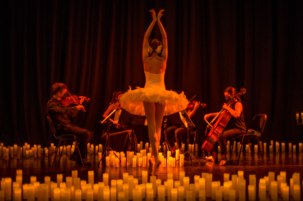 A ballerina spinning in front of a string quartet surrounded by candles.