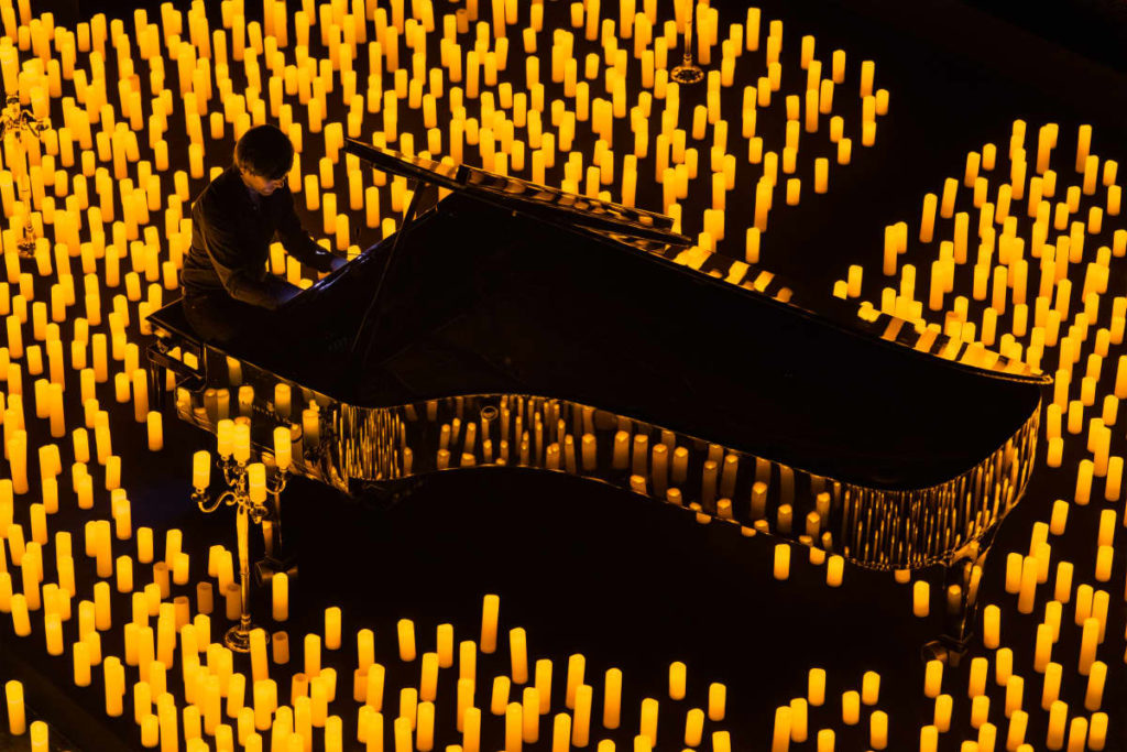 Pianist plays while surrounded by candles