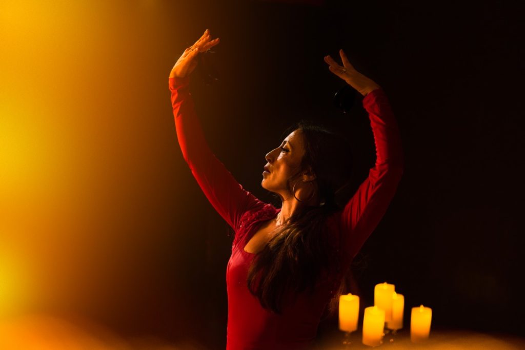 A flamenco dancer performing on stage with candles in the background