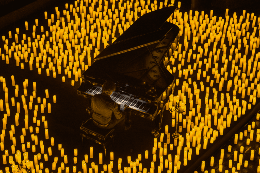 A musician playing the grand piano amid a sea of candles