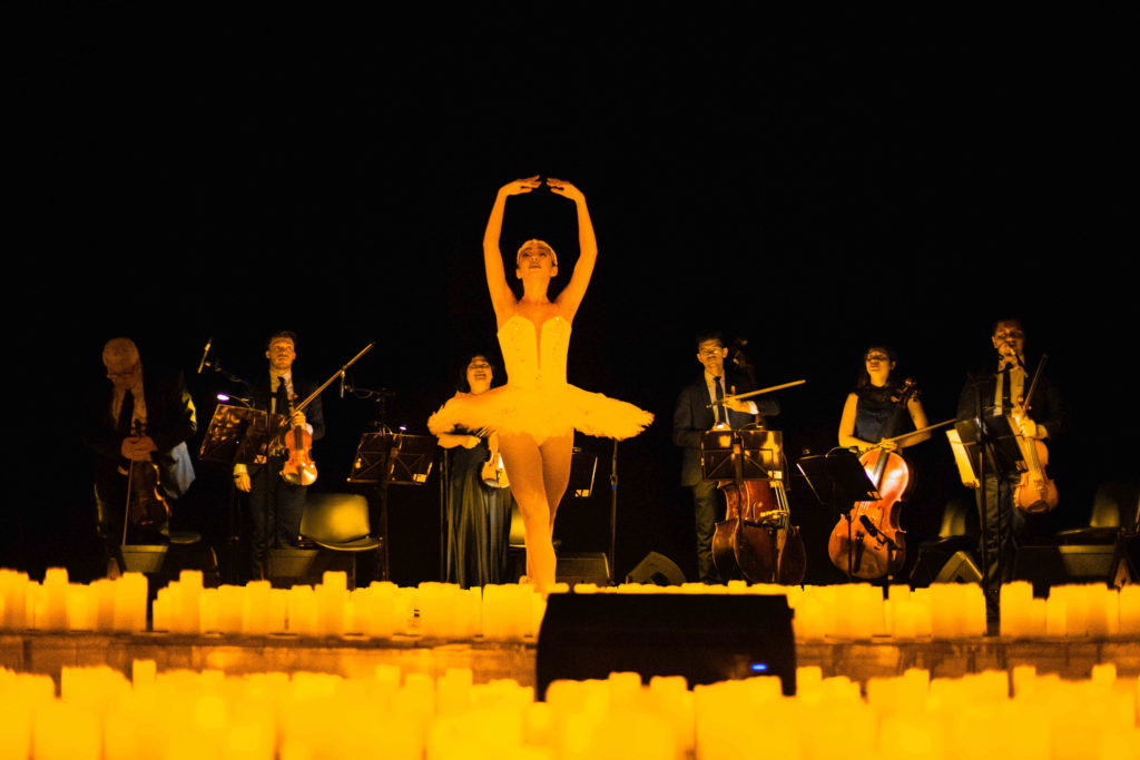Uma bailarina dança, cercada por velas no Theatro José de Alenca.