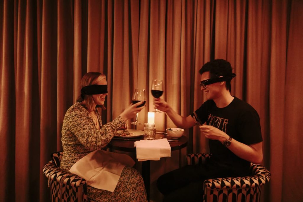 Couple making a toast at a Dining in the Dark experience