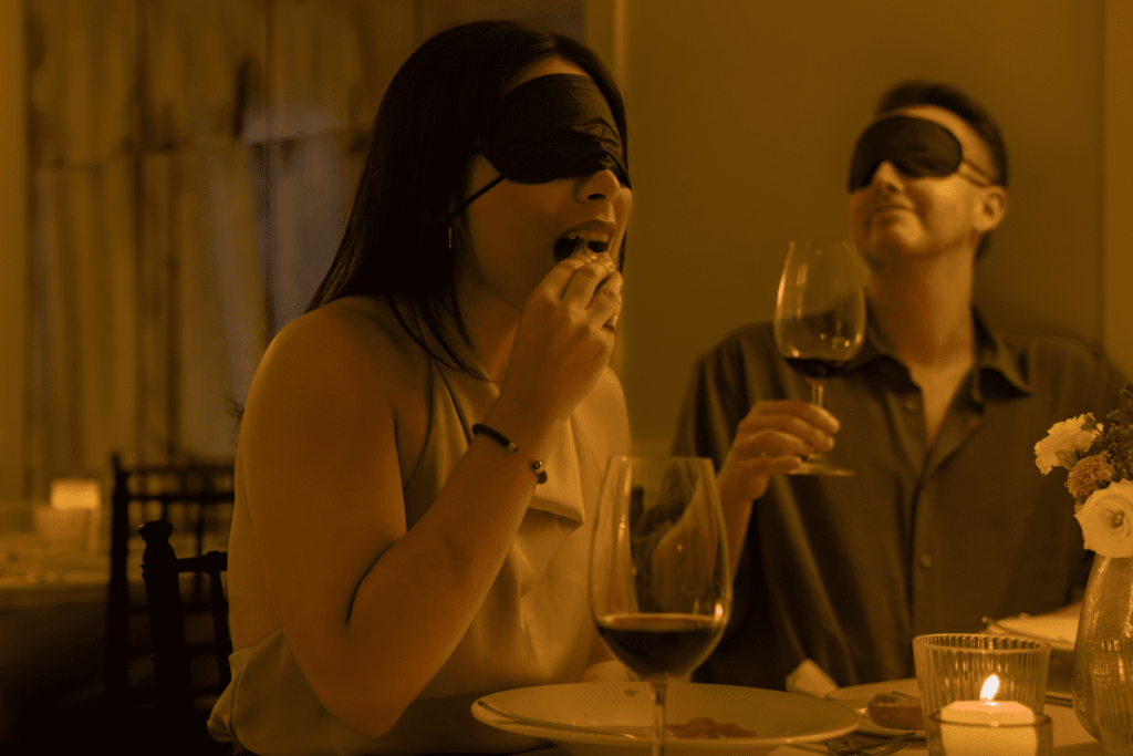 A couple eating and drinking at a Dining in the Dark experience
