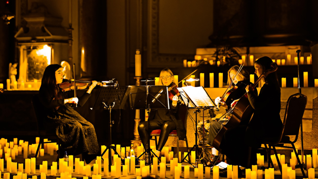 A string quartet performing on a stage filled with candles
