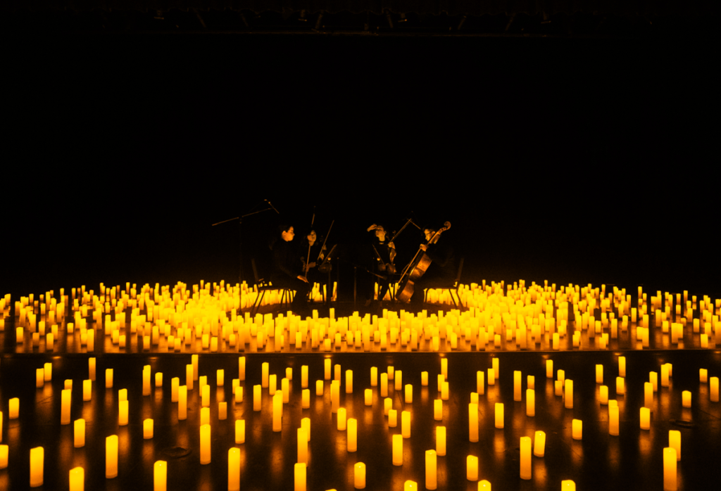 A string quartet performing on a stage surrounded by candles for a Candlelight performance.