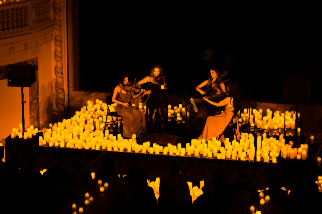 A string quartet performing a Candlelight concert on a stage surrounded by flickering candles.