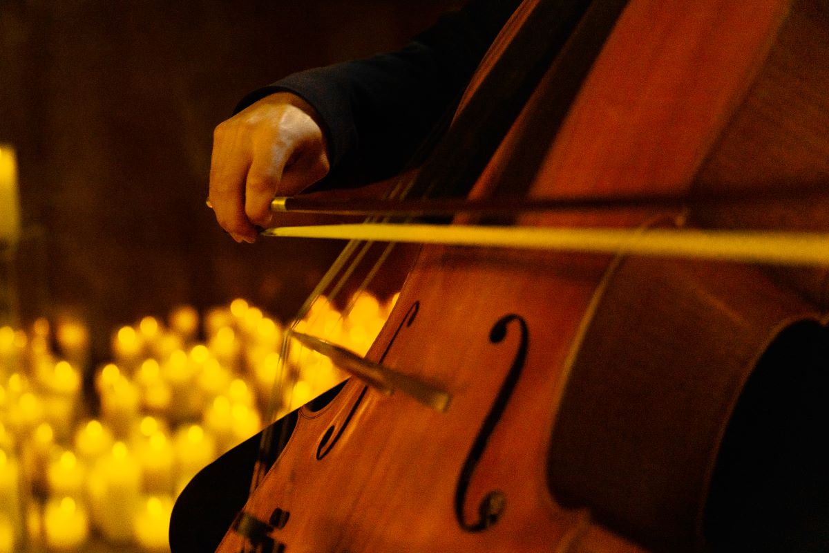 A close up of a cello being played by candlelight.