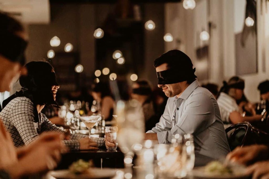 A man sitting blindfolded at the Dining in the Dark experience.