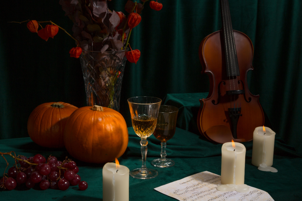 Pumpkins, candles, a glass of wine and a violin on a table