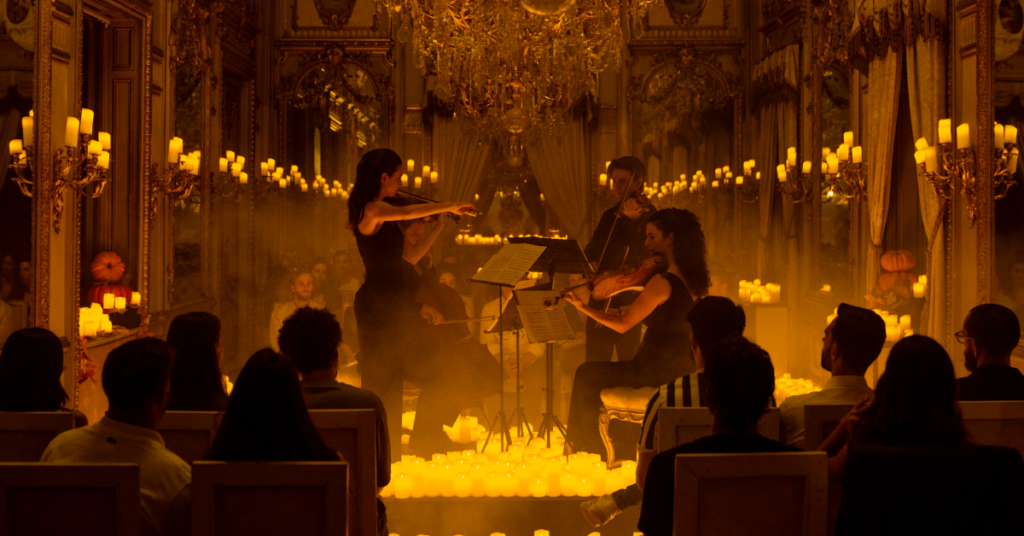 A string quartet performing in front of audience members, amid a sea of candles