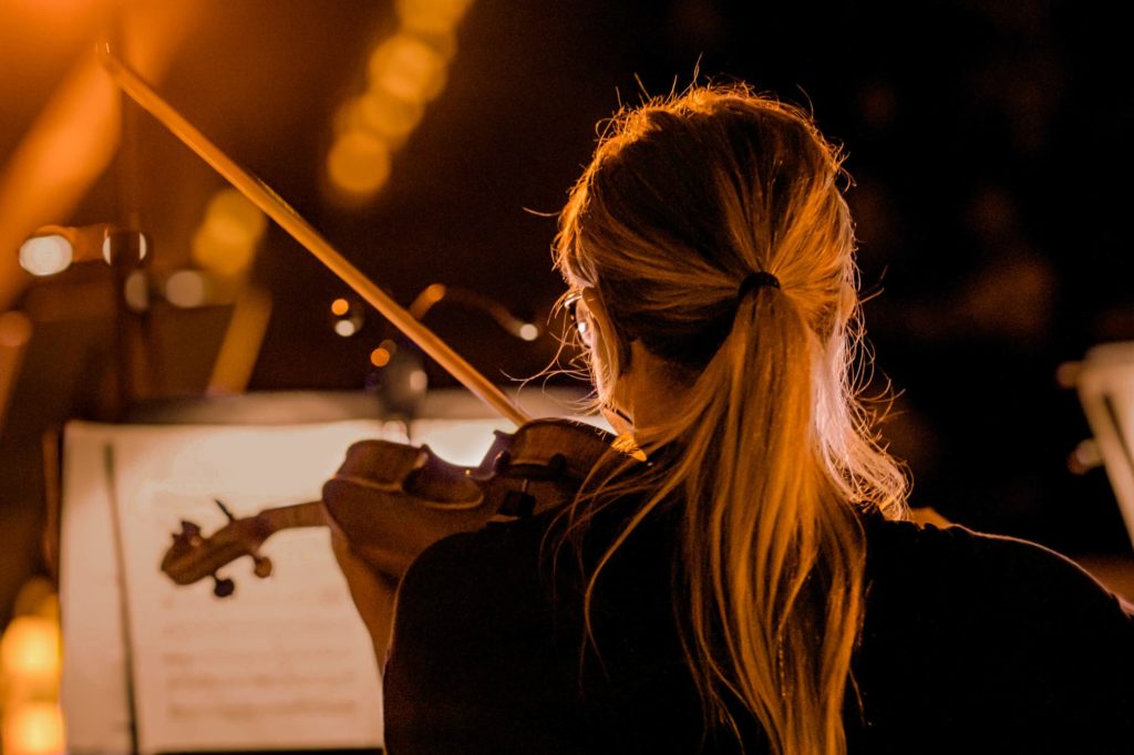 Photo en gros plan de dos d'une violoniste jouant du violon pour un concert Candlelight