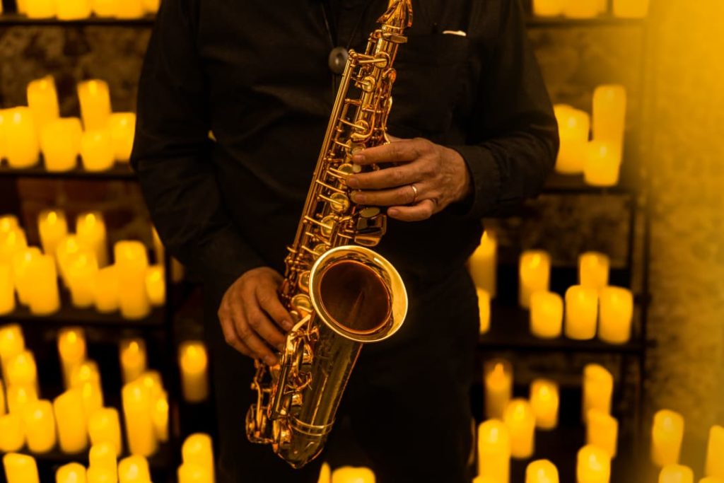Photo en gros plan d'un saxophoniste jouant pour un concert Candlelight entouré de bougies