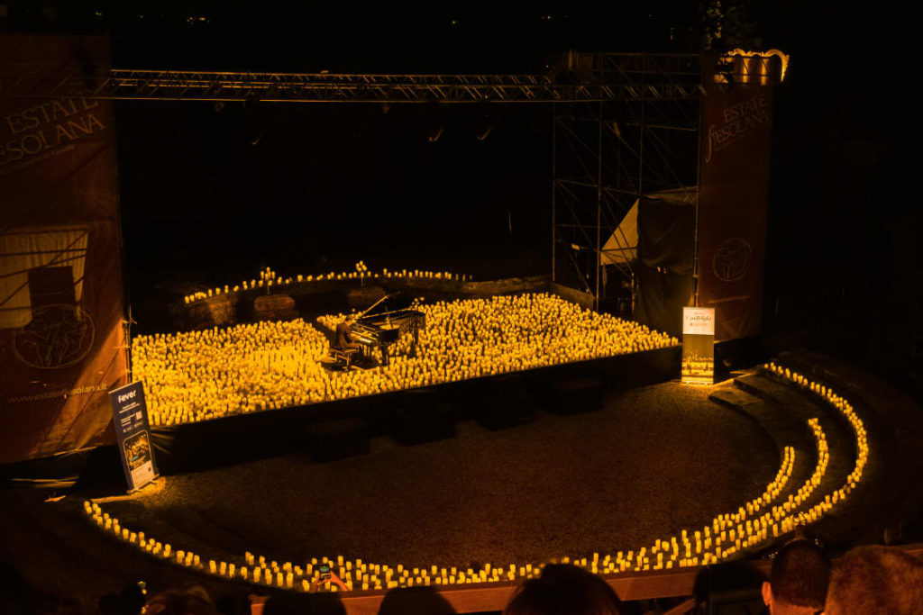 Un'ampia inquadratura del Teatro Romano di Firenze pieno di candele durante un concerto a lume di candela
