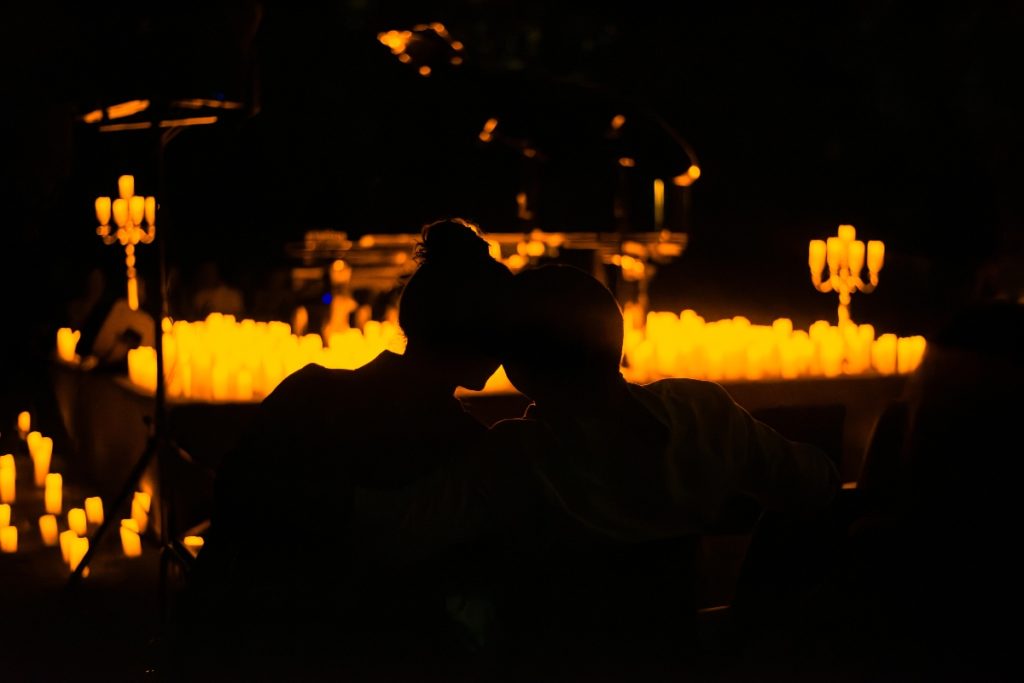 silhouette of couple in front of piano and thousands of candles for candlelight concert