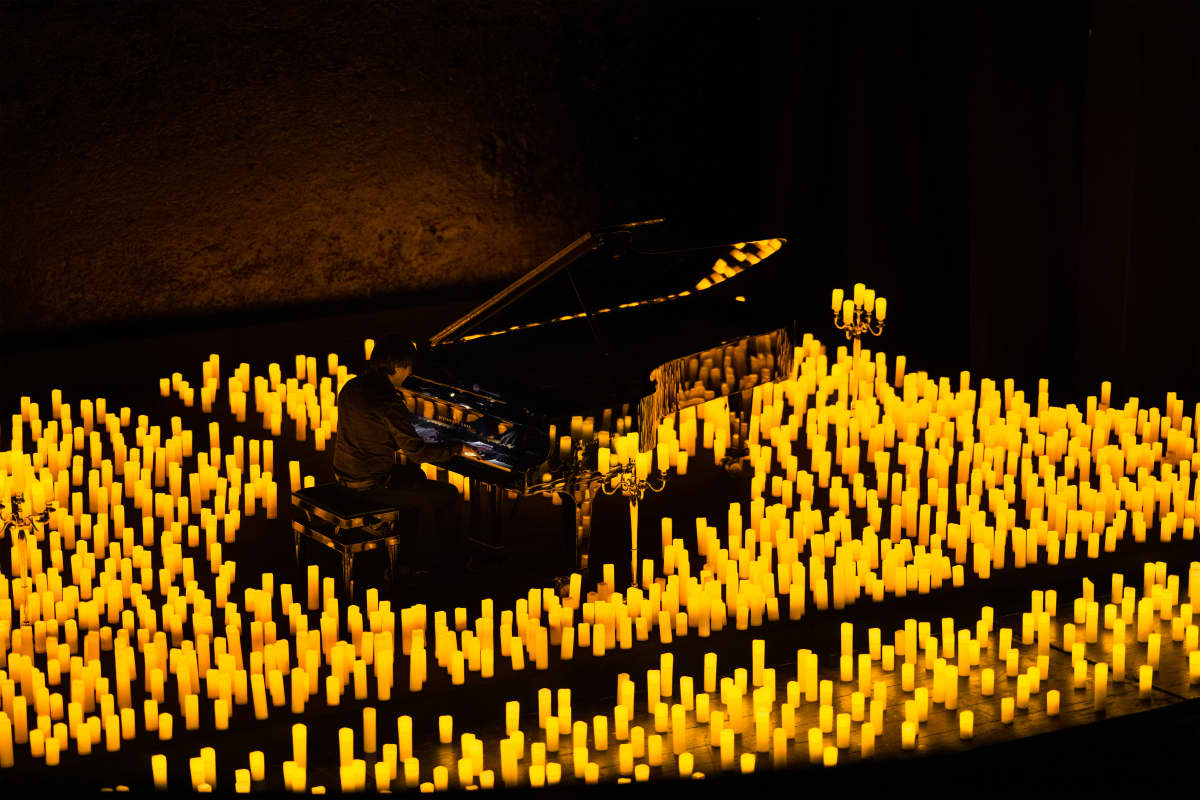 A pianist performing while surrounded by a sea of candles