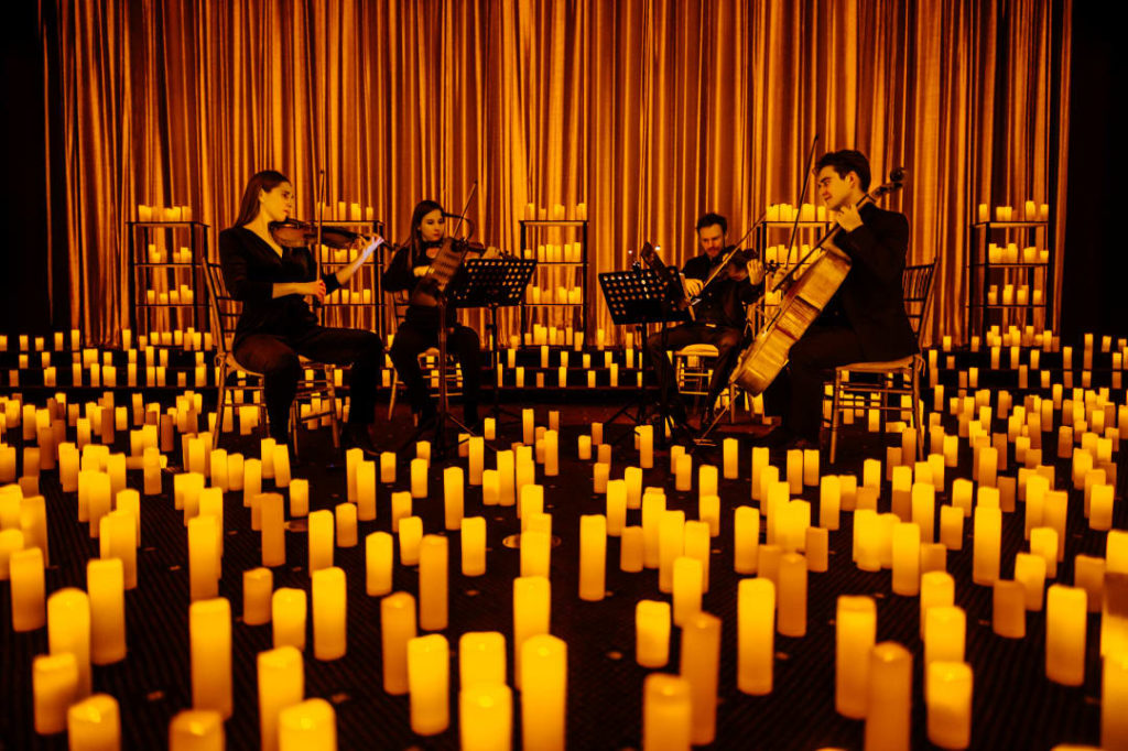 A string quartet perform, surrounded by candles.