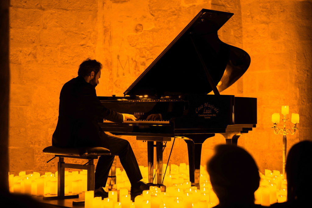 A pianist plays, surrounded by candles at a Candlelight concert.