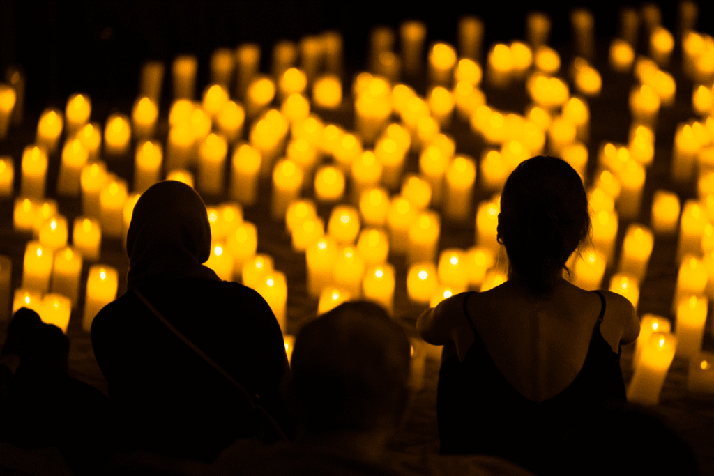 An audience looking out across a sea of candlelight.