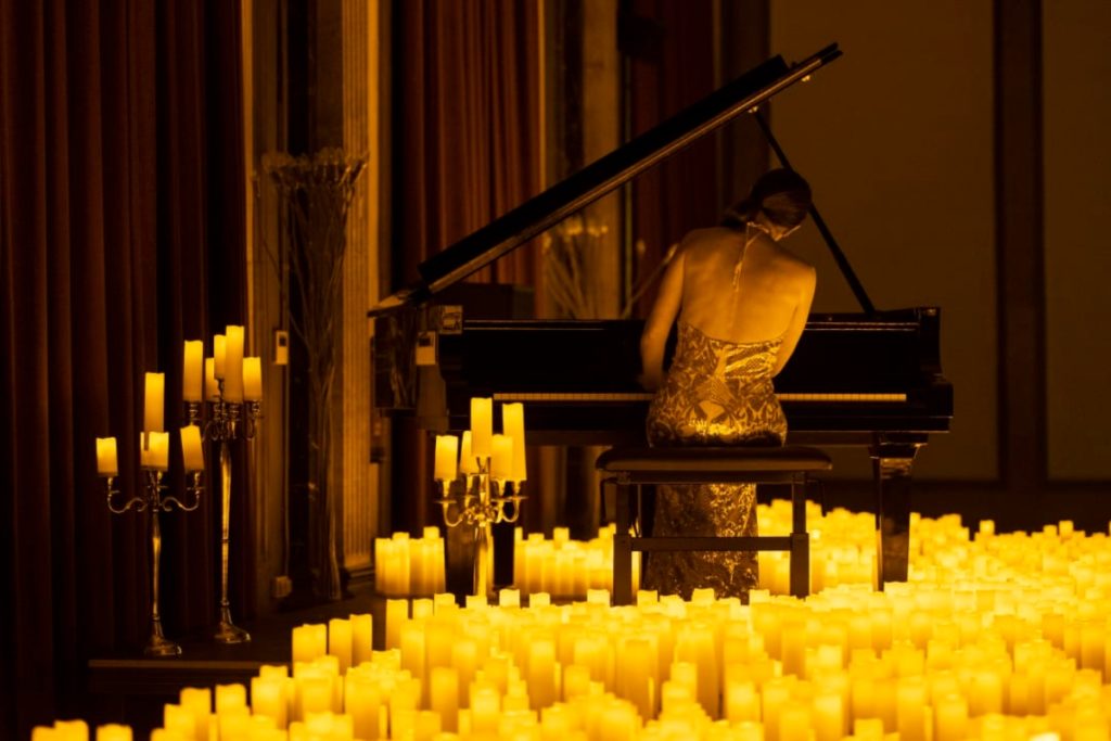 A musician playing the gran piano amid a sea of candles.