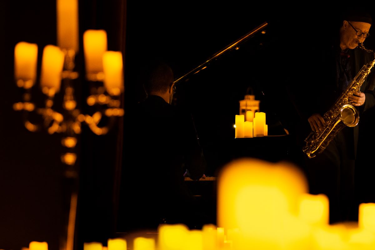 A man playing the sax beside a pianist at a Candlelight concert.