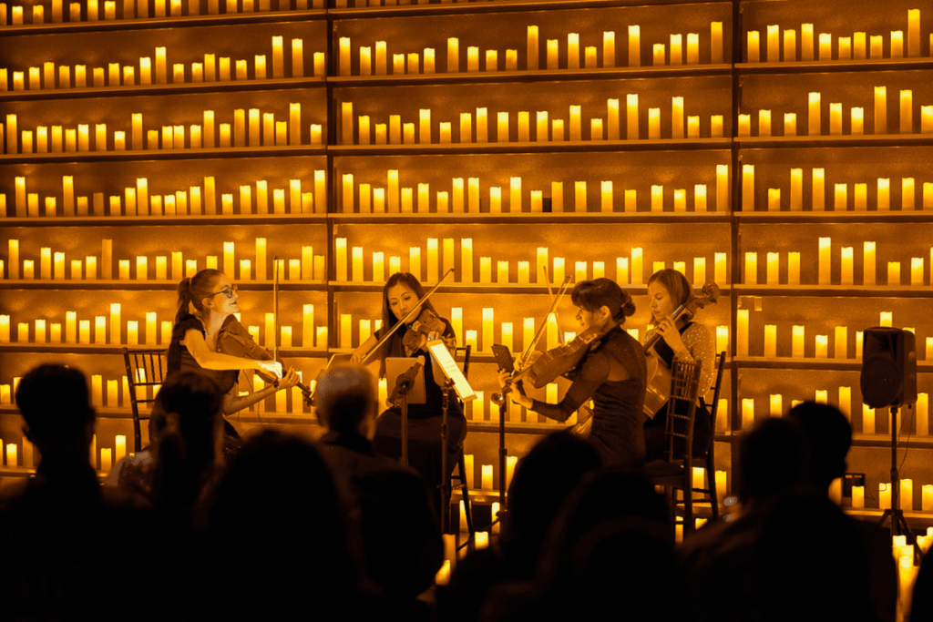 a string quartet performing on stage by candlelight