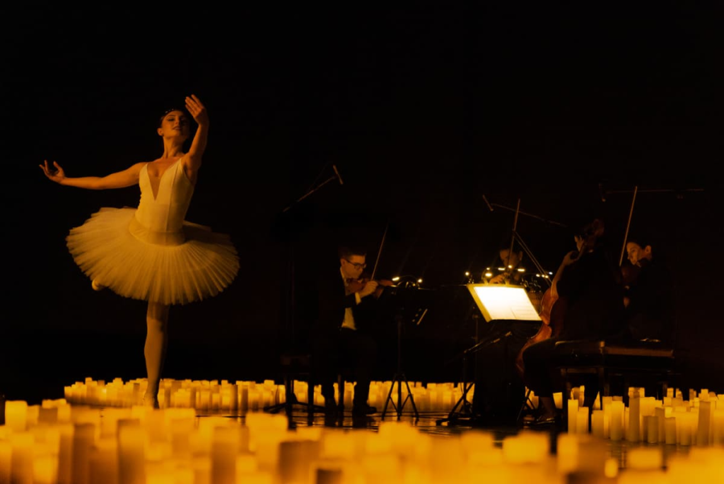 A ballet dancer and a string quartet performing amid a sea of candles