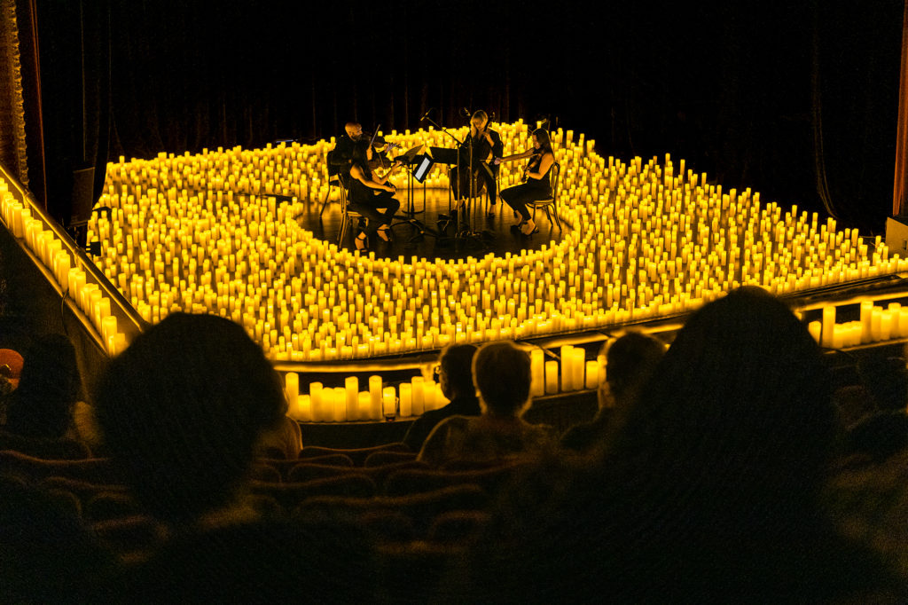 A string quartet performing amid a sea of candles