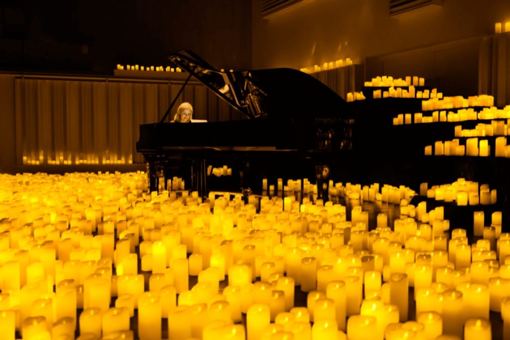 A pianist performing amid a sea of candles.