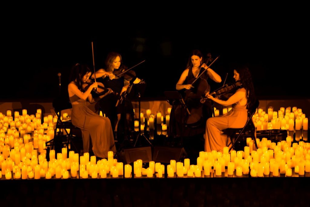 Kwartet smyczkowy wykonujący koncert przy świecach.