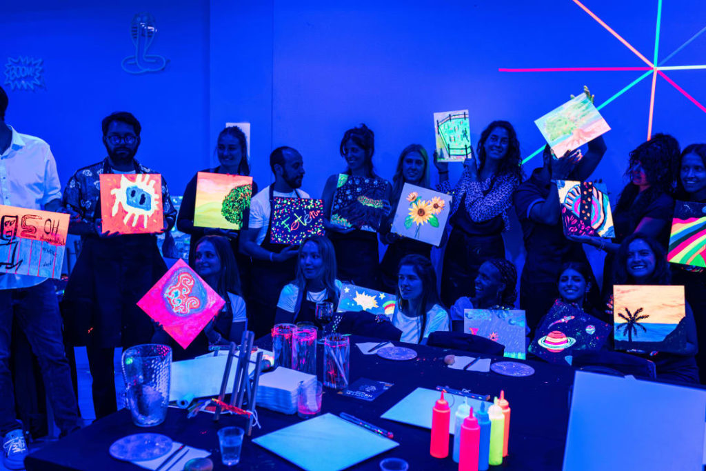 Photo d'un groupe de personnes montrant leurs peinture réalisées lors de l'atelier Neon Brush