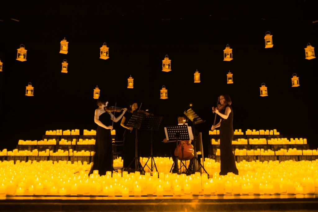 A string quartet performs, surrounded by candles. 