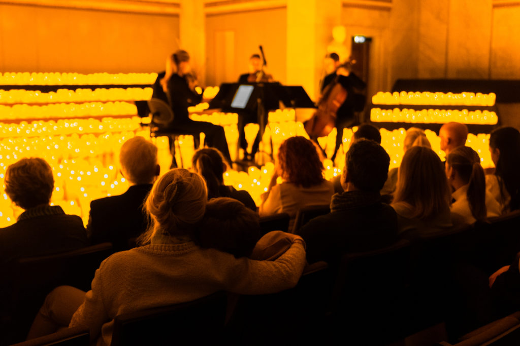 Musicians perform in front of candles and a crowd at Candlelight.