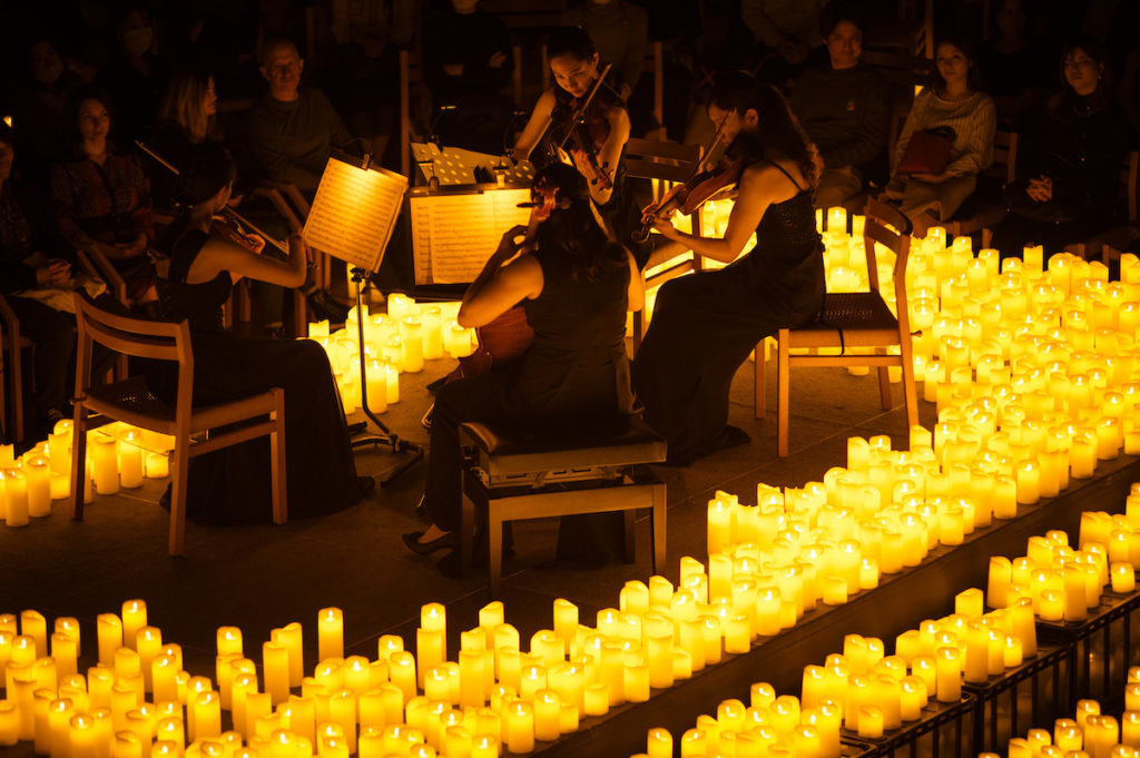 A string quartet performing amid a sea of candles