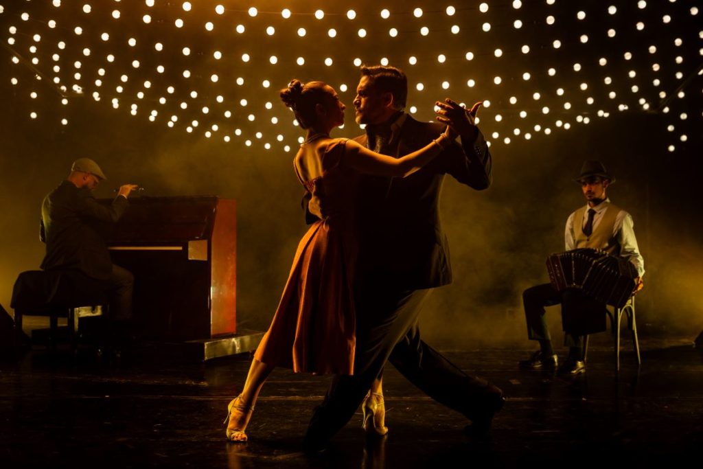 Two professional dancers performing the tango under fairylights alongside a piano and bandoneon player at We Call It Tango.