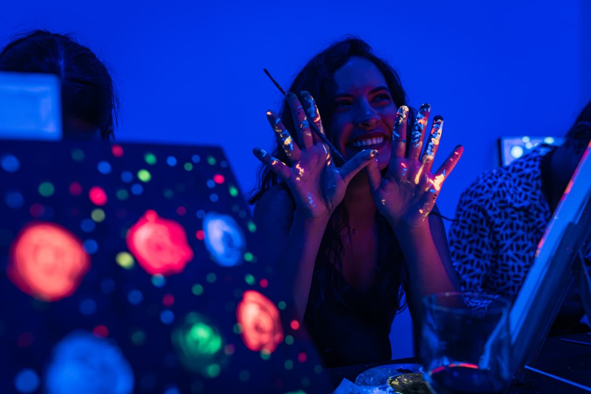 A girl holding her hands out covered in neon paints at Neon Brush