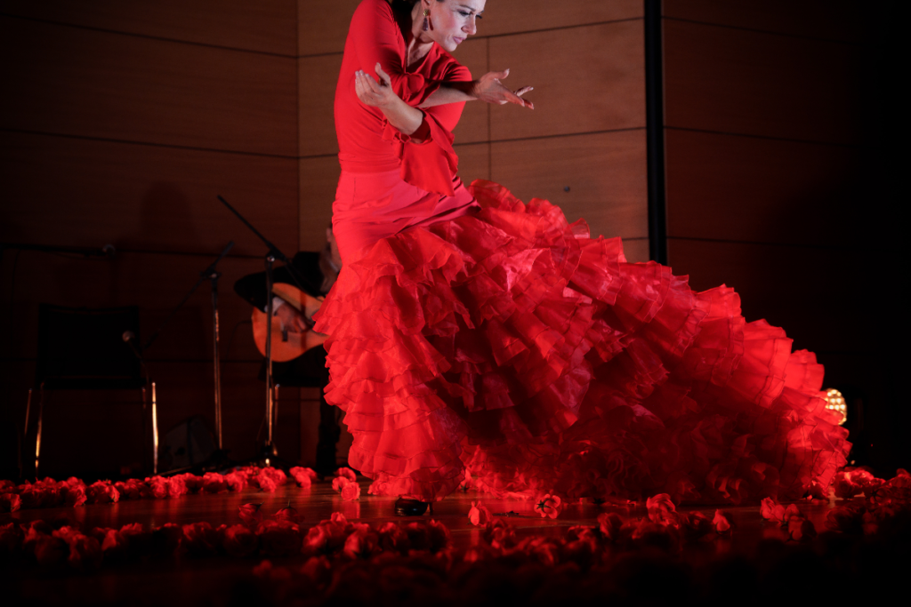 Een vrouw in een rode jurk danst bij We Call It Flamenco.